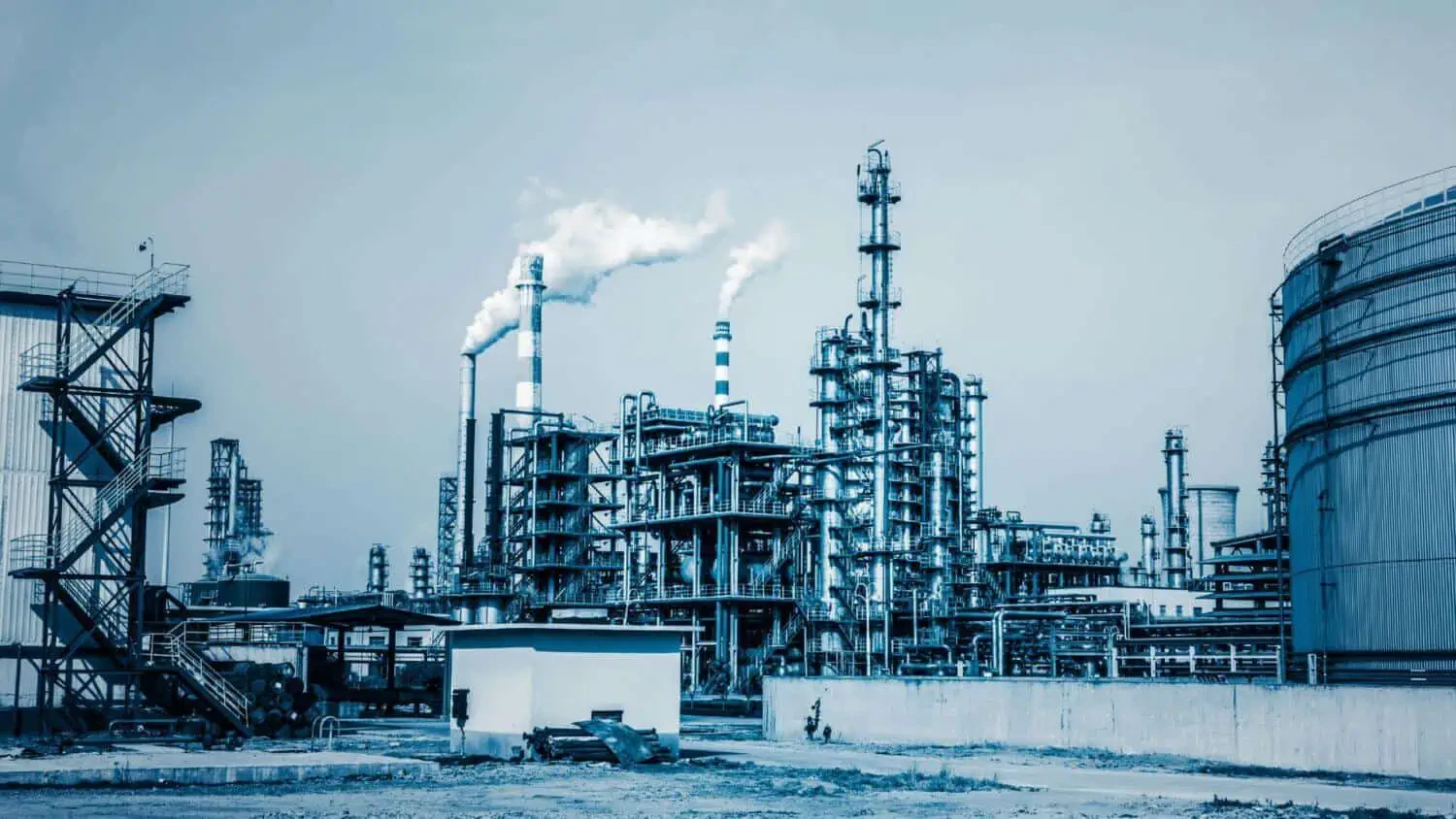 Raffineria industriale con ciminiere e serbatoi