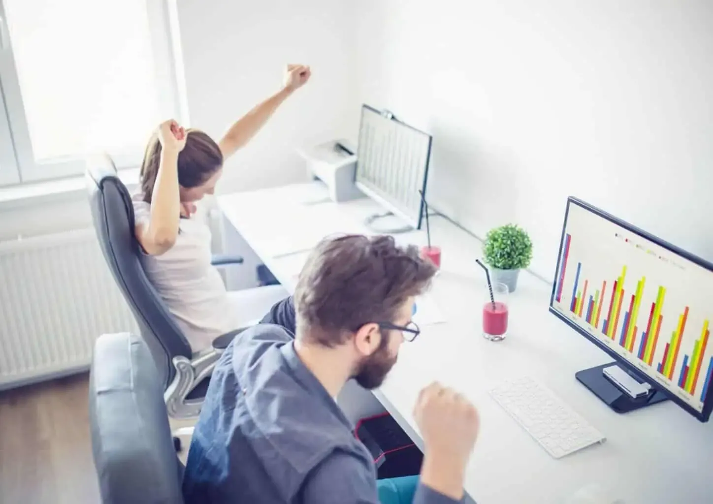 Two people celebrating success with business charts.