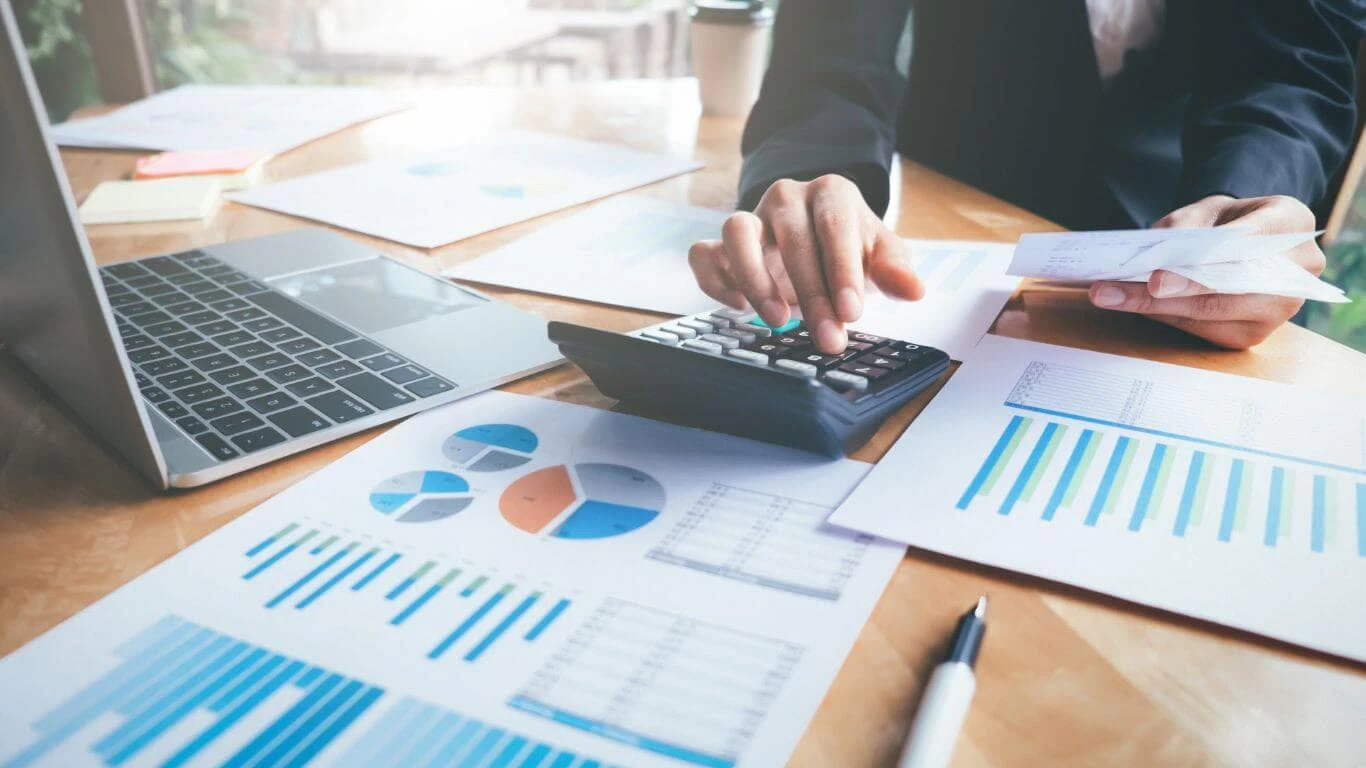 Persona che calcola le finanze con un computer portatile e grafici.