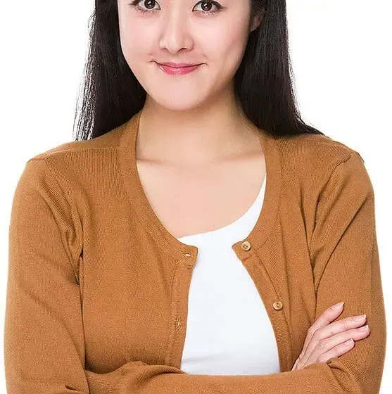 Smiling person in brown cardigan, arms crossed