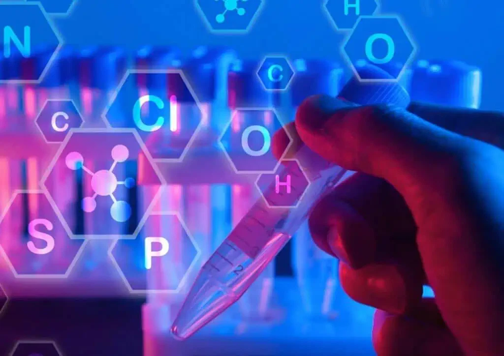 La mano tiene una provetta con sovrapposte le formule chimiche.