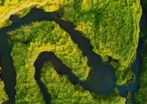 Luchtfoto van een kronkelende rivier door een groen landschap.
