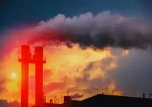 Fabrieksschoorstenen stoten rook uit tegen de vlammende avondlucht.