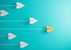 Vliegende papieren vliegtuigjes, één gele voorop