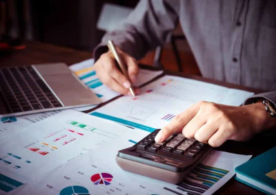 Persona che calcola il budget con grafici finanziari.